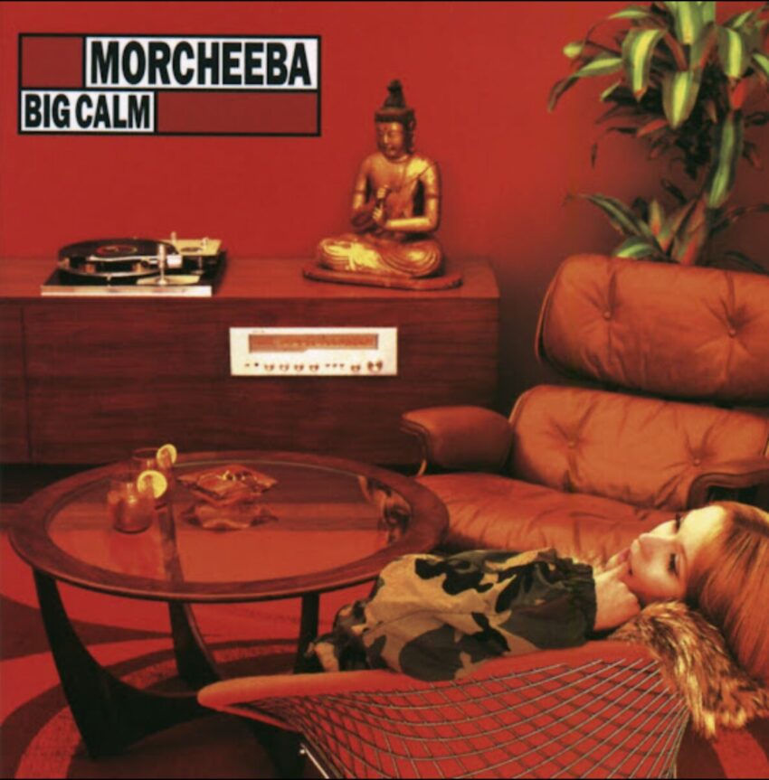 Cover art of Morcheeba's 1998 album "Big Calm": A mid-century modern-ish room with a blond girl in a chair. O the far wall is a phonograph with an album on it next to a status of the Buddha. Two drinks are on the table.